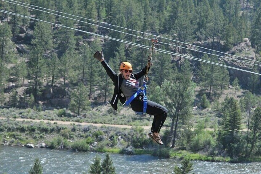 A person zip-lining over a river with a forested landscape in the background. 3