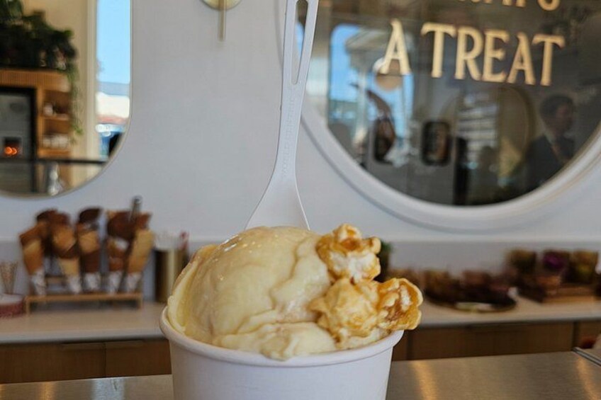 A cup of ice cream with a waffle cone on top, placed on a counter with a window in the background. 2