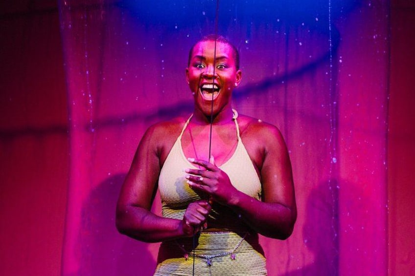 A person in a stage setting with a curtain backdrop. 3