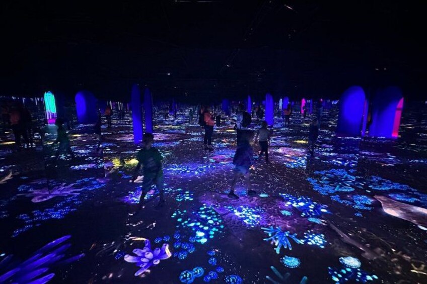 A dark room with people walking on a floor covered with blue and purple lights. 4