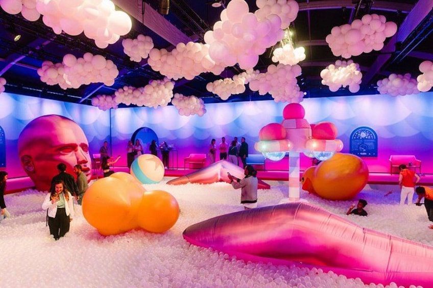 A colorful indoor play area with large inflatable structures and a stage. 2