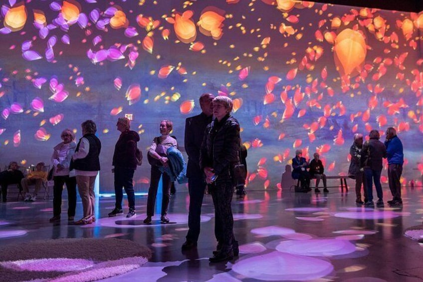 A group of people at an event with a large digital display of floating lanterns. 2