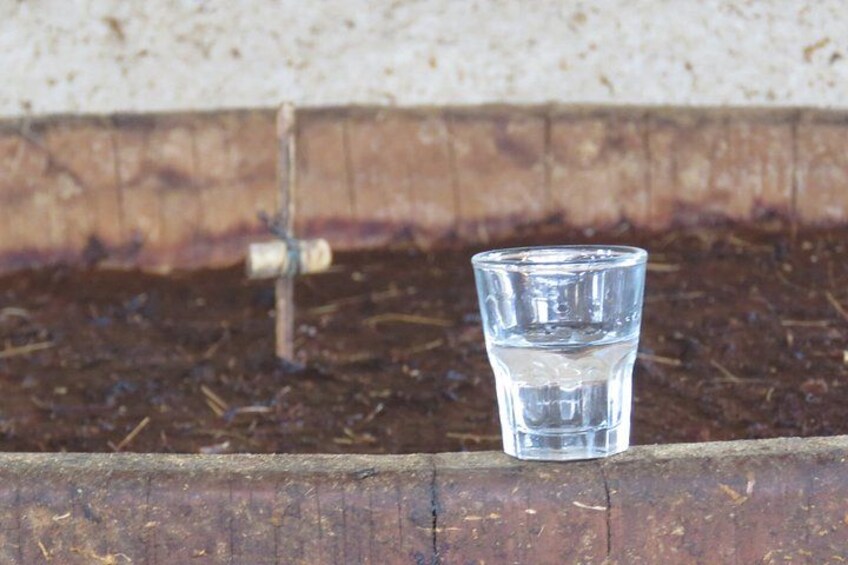 A glass of water on a wooden ledge with soil and a metal pipe in the background. 4