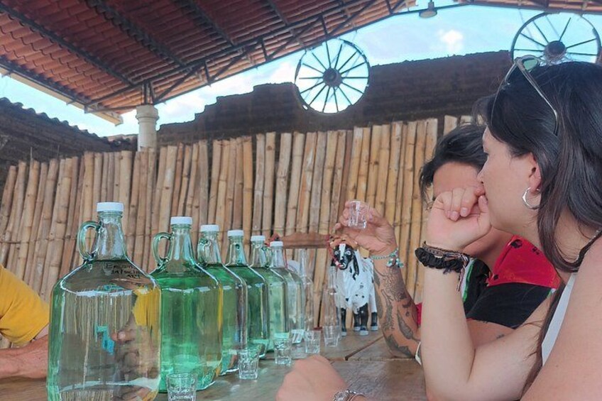 A group of people sitting at a table with large glass bottles and glasses. 2