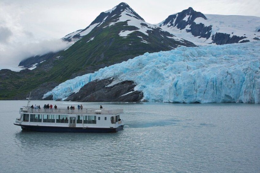 A boat on calm water with a glacier and mountains in the background. 5