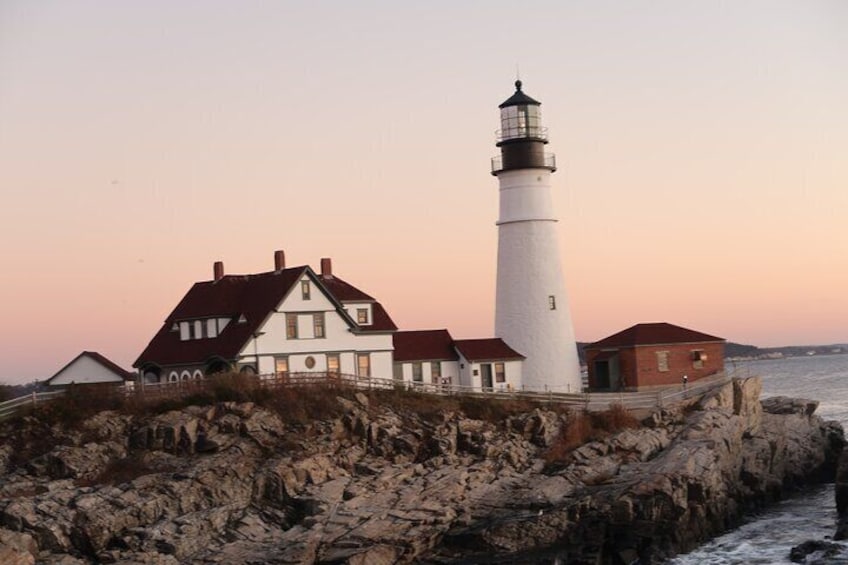 A white lighthouse, a white house with a red roof, and a rocky shoreline. 1