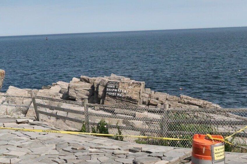 A historical shipwreck site with a fenced area and a signboard. 4