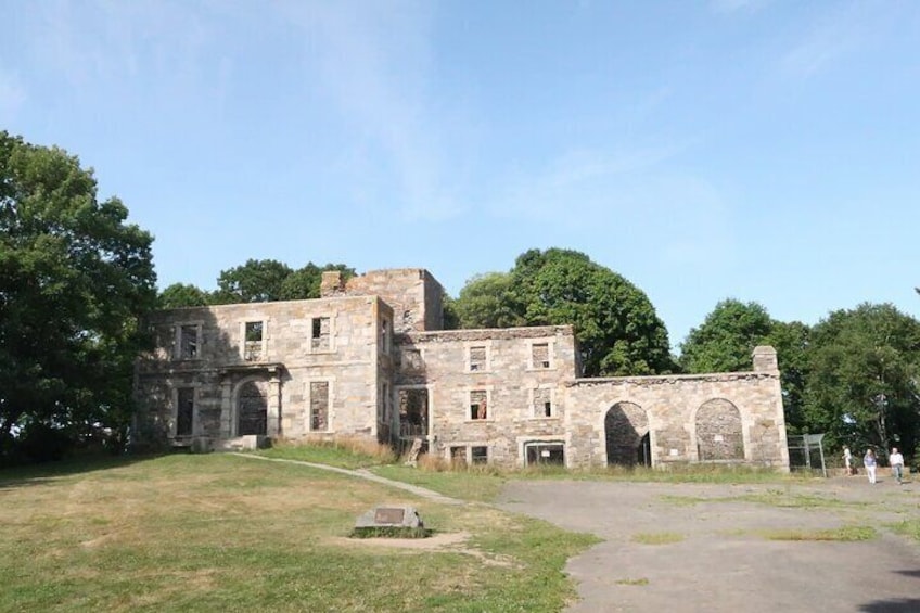 An old stone building with arched doorways and a grassy area in front. 3