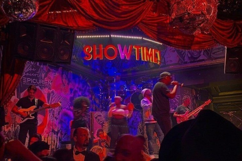 A band performing on a stage with a 'SHOWTIME' sign, surrounded by a crowd. 5