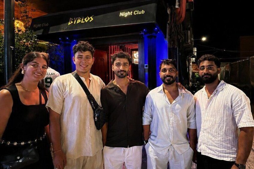 A group of people standing in front of a building with a sign that reads 'Night Club.' 1