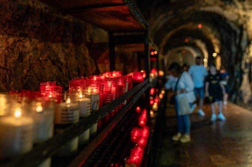 A tunnel with candles on shelves and people walking. 2