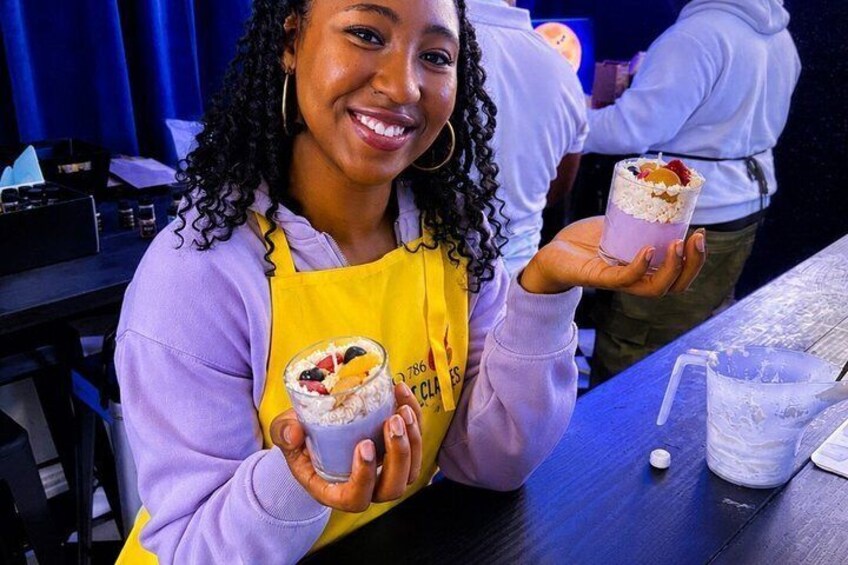 A person holding two dessert cups with toppings. 5