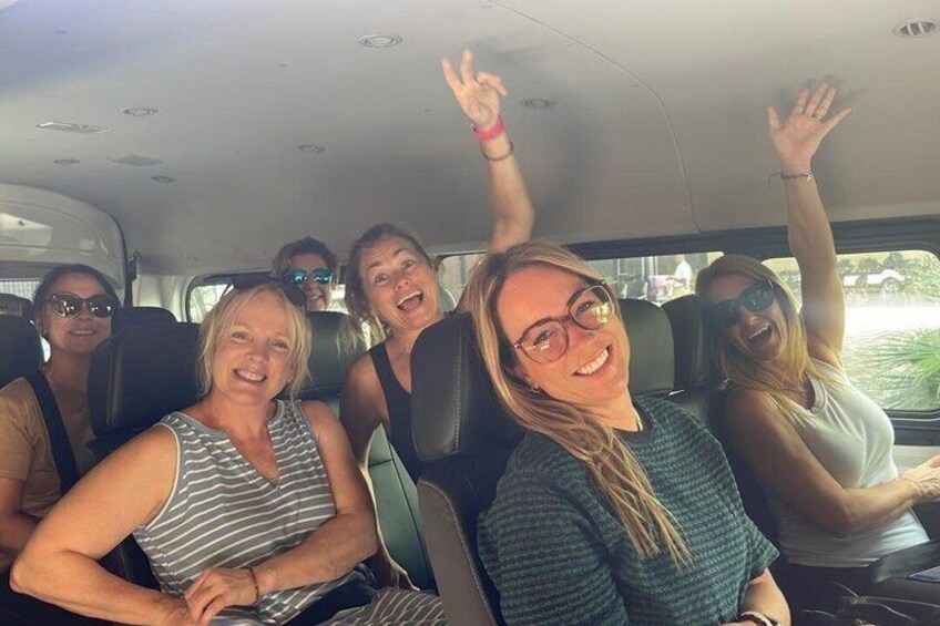 A group of people in a vehicle with their hands raised. 1