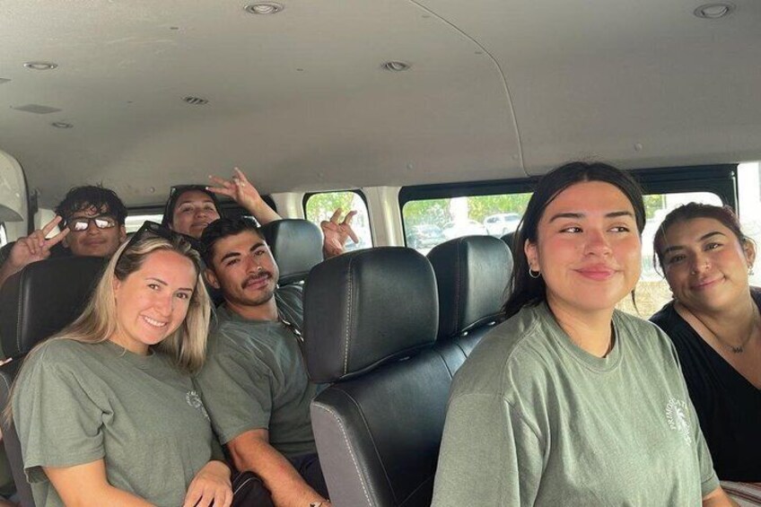 A group of people seated in a vehicle with black leather seats and a visible window. 4