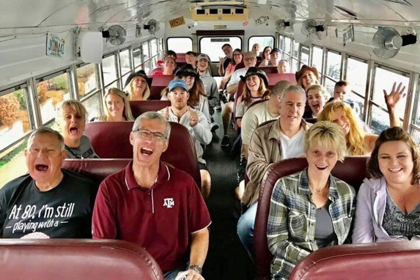 A group of people seated inside a bus with large windows. 1