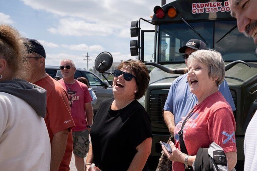 A group of people standing near a vehicle with a sign that reads 'REDNECK B 615 316-00.' 2