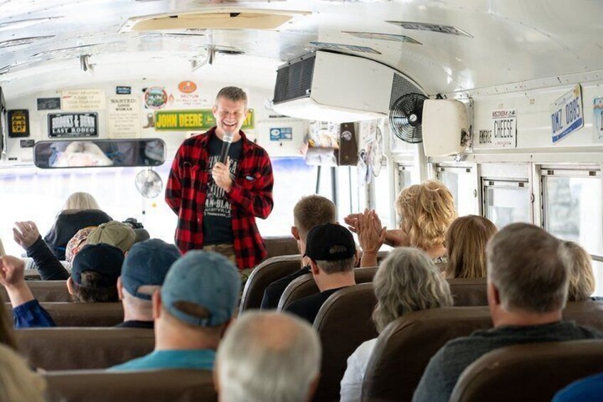 A person speaking to an audience inside a bus with various signs and advertisements. 3