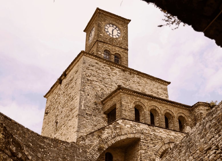 A historic stone tower with a clock, arched windows, and a weathered facade. 1