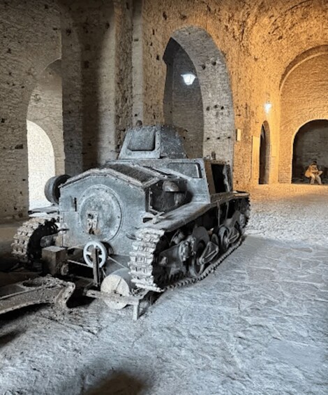 A tank in a stone-walled room with arched ceilings and a person in the background. 2