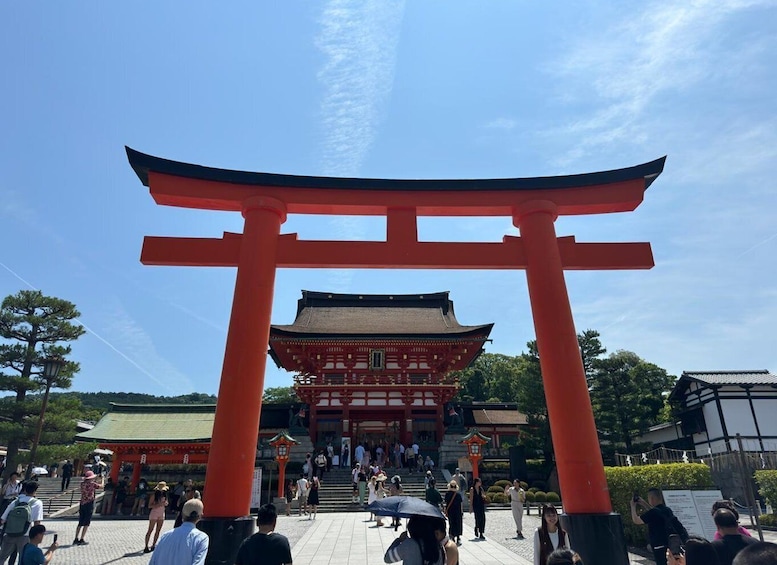 A traditional Japanese torii gate with a pagoda in the background, surrounded by visitors. 1