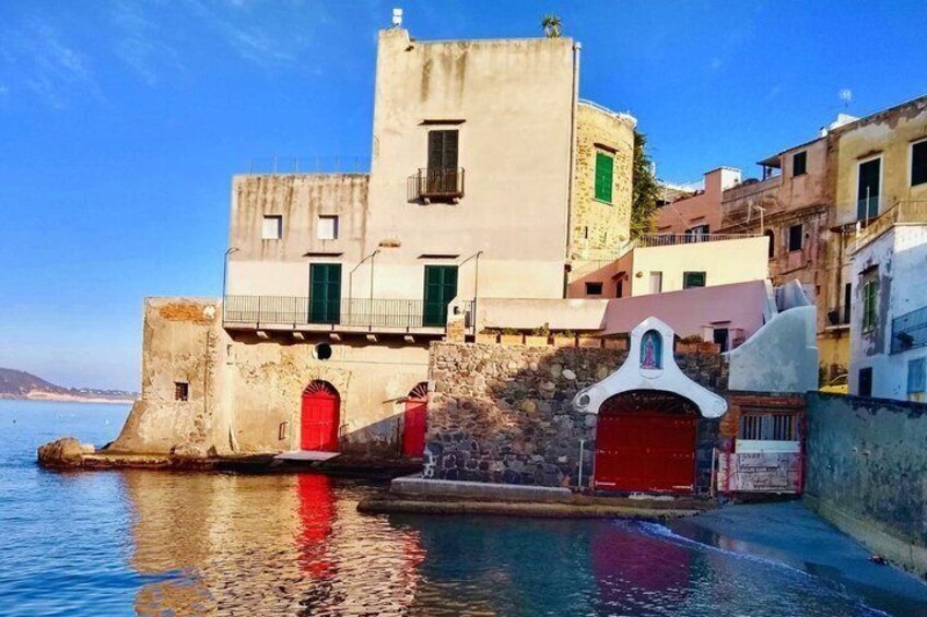 A coastal building with a red door, a white facade, and a stone wall. 3