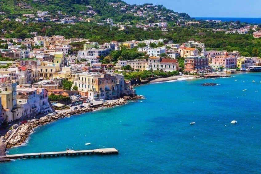 A coastal town with colorful buildings, a pier, and clear blue waters. 2