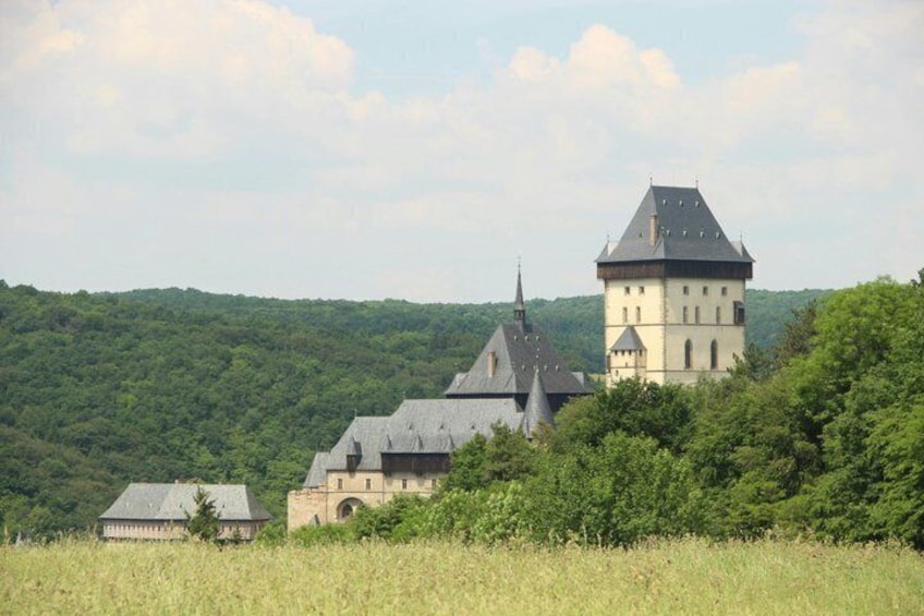 A castle with a tower and a smaller building amidst a lush green landscape. 3