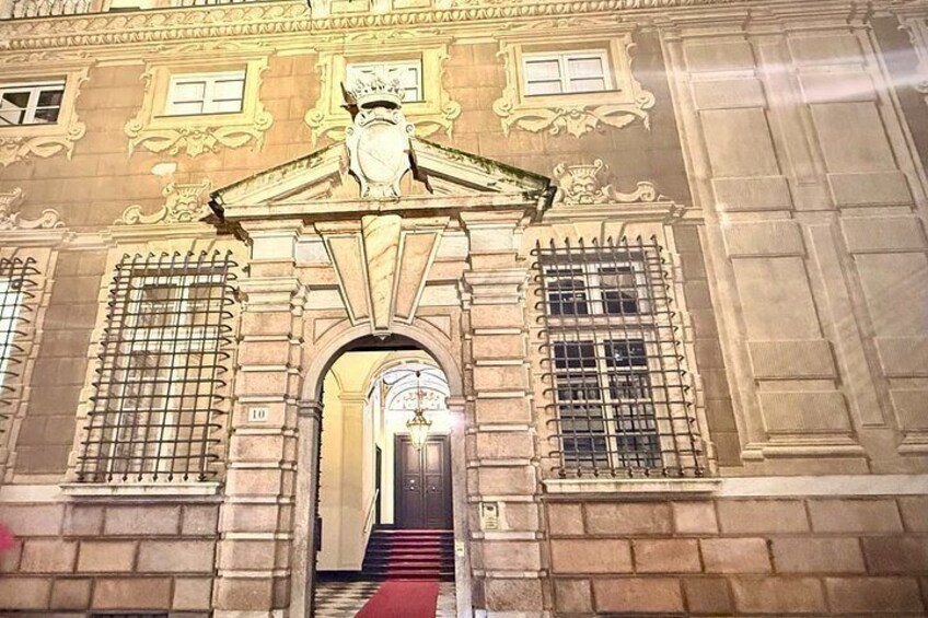 A grand entrance with a red carpet, ornate columns, and a statue above the doorway. 2
