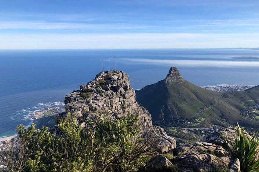 A rocky mountain peak with a cross, overlooking a coastal town and the ocean. 4
