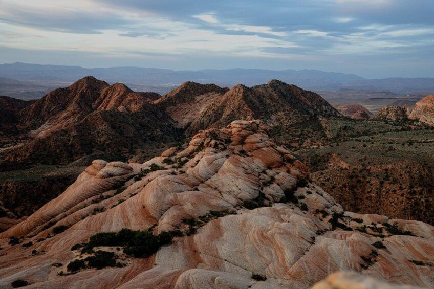 A mountainous landscape with layered rock formations and distant hills. 4
