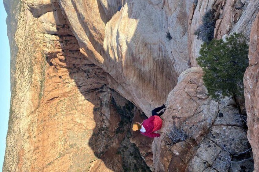 A person in red climbing a rocky cliff. 2