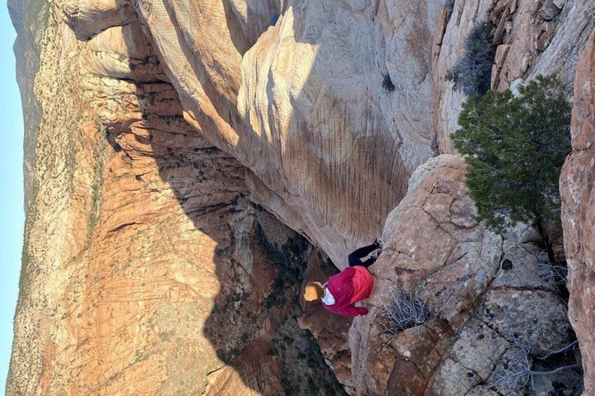 A person in a red jacket climbing a rocky cliff. 2
