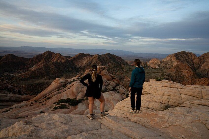 Two people standing on rocky terrain with a mountainous landscape in the background. 5