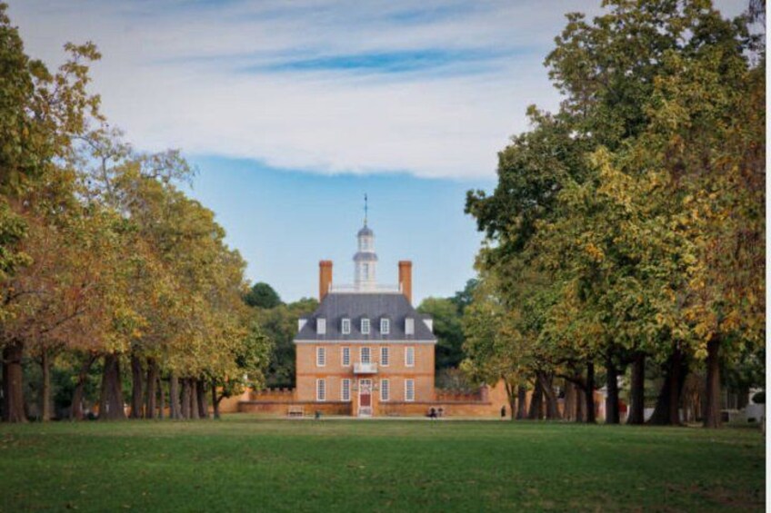 A large brick building with a central tower, surrounded by a well-maintained lawn and trees. 1