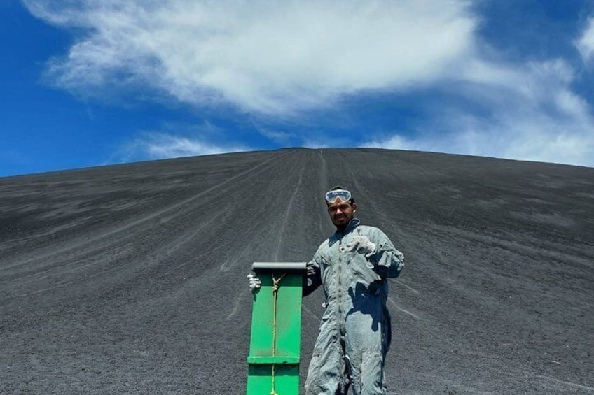 A person in a white protective suit standing on a flat, dark surface with a green object in front of them. 4