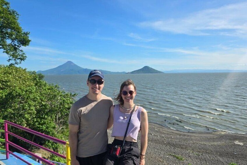 A couple standing by a body of water with a mountain in the background. 3