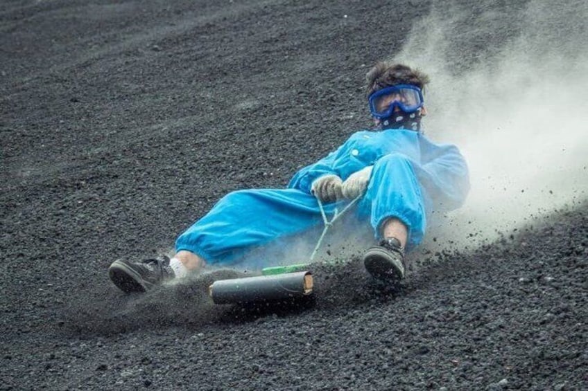 A person in blue protective gear sliding on a sled across a rough, dark surface. 2