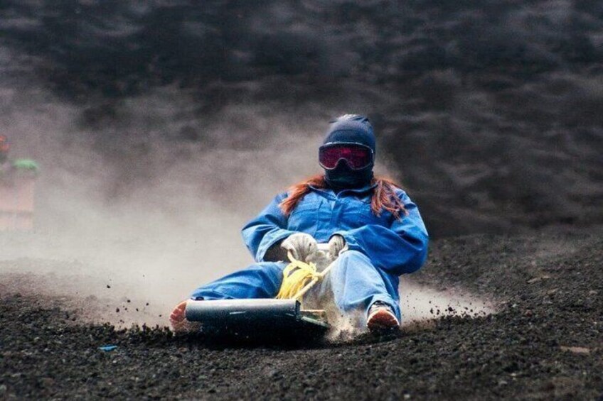 A person in a blue suit and helmet sliding on a surface with dust. 1