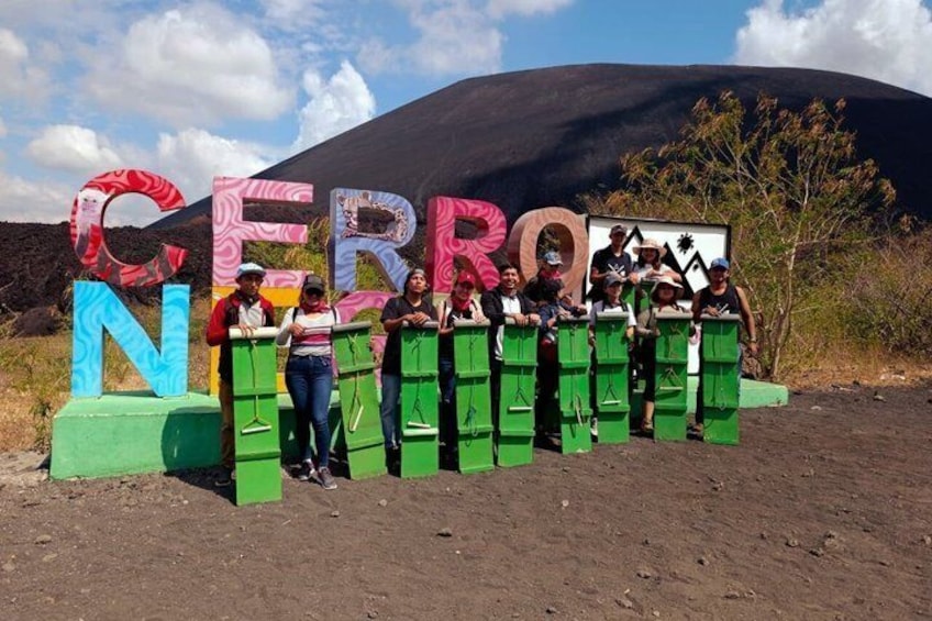 A group of people standing in front of a large sign with colorful letters spelling 'CERRO N.' 3