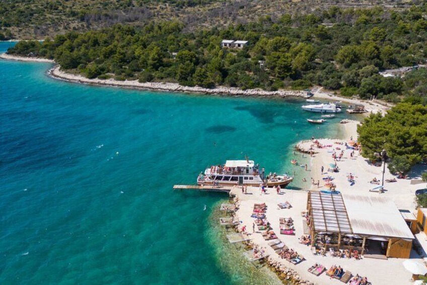 A coastal area with a boat docked near a beach, surrounded by lush greenery and clear turquoise waters. 4