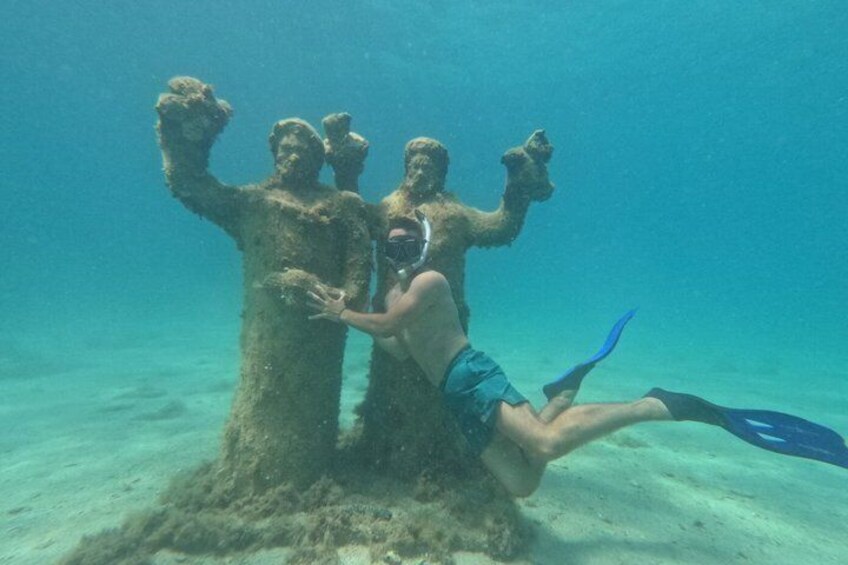 A diver underwater near a submerged statue. 1