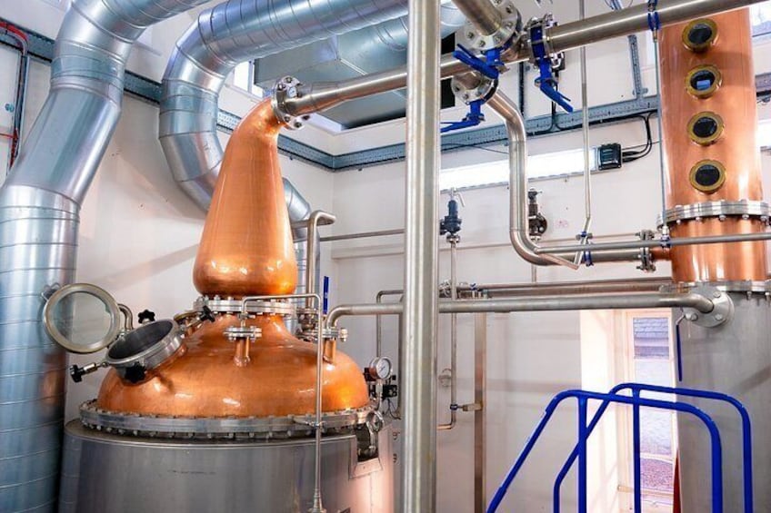 A copper distillation apparatus with pipes and valves, set in an industrial environment. 4