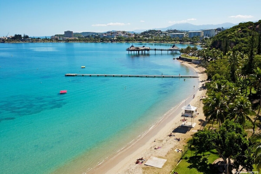 A coastal beach with clear turquoise waters, a pier, and a resort area. 5