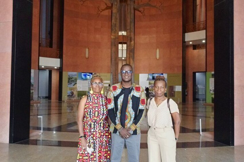 Three people standing in a spacious lobby with a high ceiling and large windows. 5