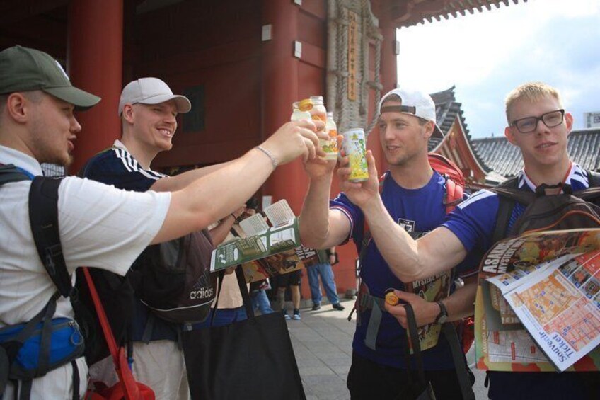 Four people toasting with drinks in front of a traditional building. 3