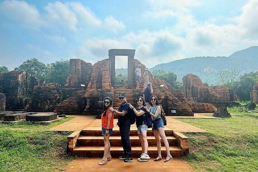 A group of people standing on a platform with ancient ruins in the background. 2