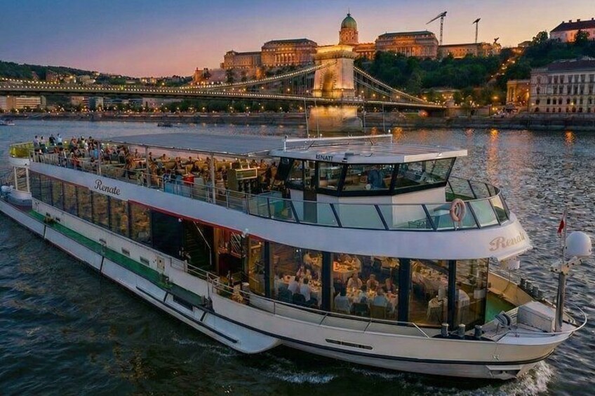 A river cruise boat named 'Renate' with passengers, a bridge, and buildings in the background. 3