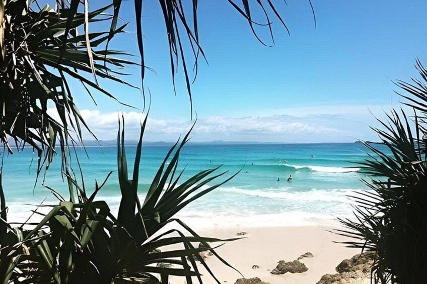A beach with clear turquoise water, white sand, and palm trees. 2