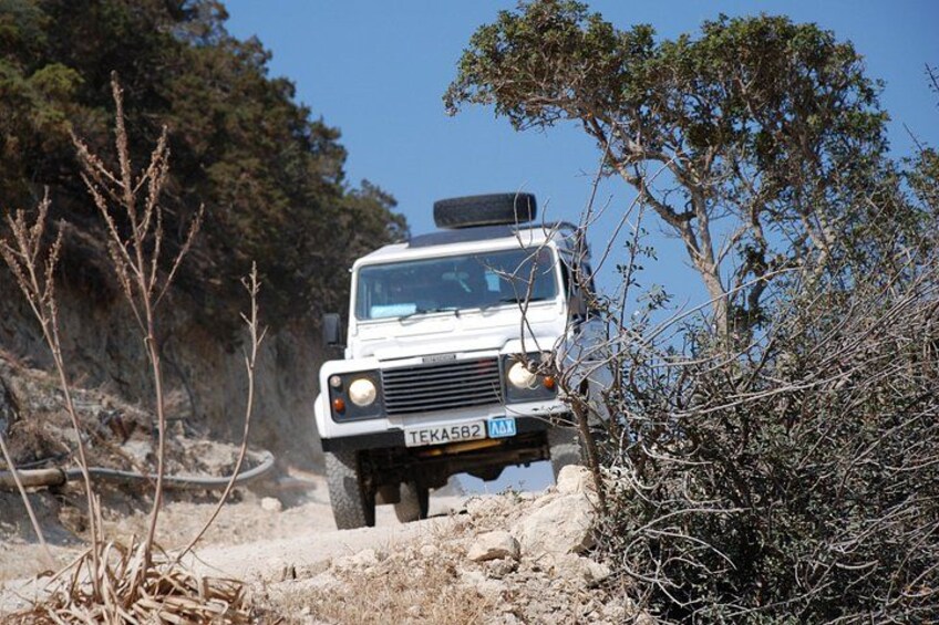 A white off-road vehicle with a license plate TEKA582 navigating a rocky terrain with sparse vegetation. 1