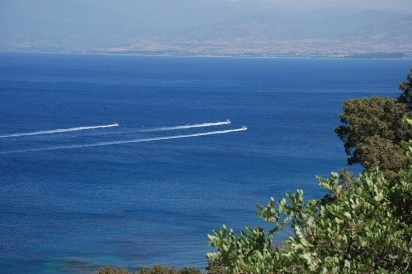 A boat creating a wake on a calm sea with a coastline in the background. 2